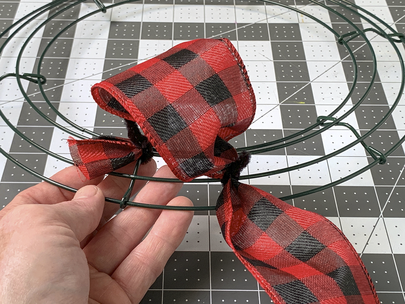 Attaching the ribbon to the wreath with a pipe cleaner